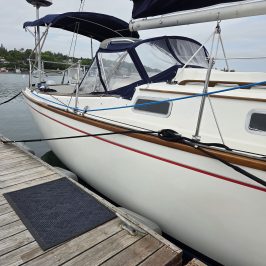 Sailboat docked with blue canopy and wooden deck.