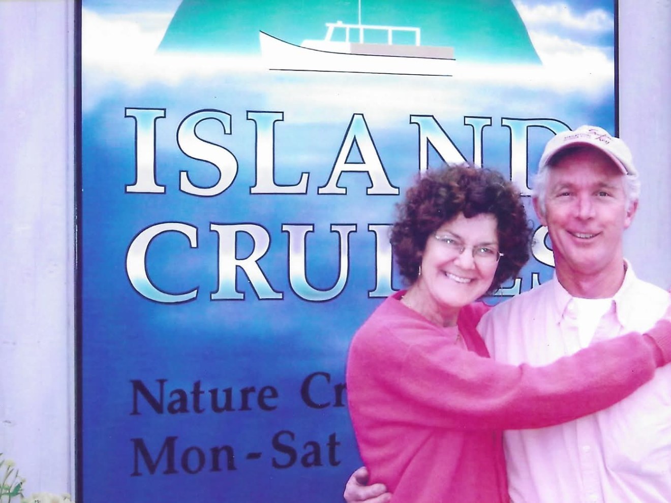 Smiling couple embracing in front of 'Island Cruises' sign.